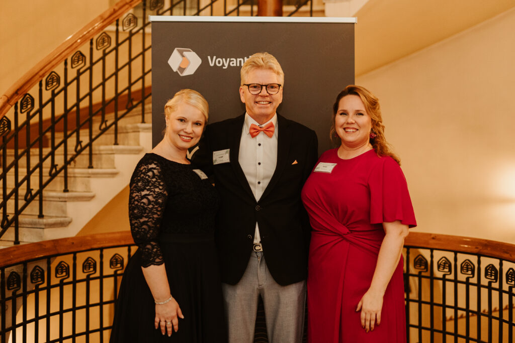 Employees posing in front of Voyantic roll up.